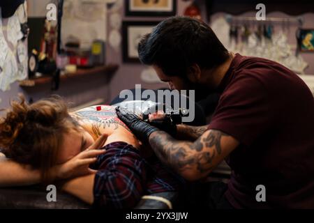 Ein Tätowierer macht ein Tattoo für einen Klienten im Studio Stockfoto