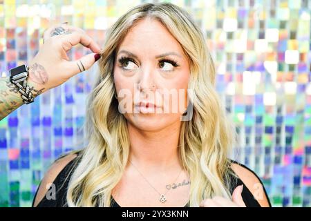 Frau mit blondem, gewelltem Haar, die Hand des Stylisten passt die Stränge an. Stockfoto