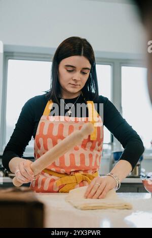 Eine Frau macht etwas in der Küche. Sie trägt eine schwarze Schürze und einen gelben Gürtel Stockfoto