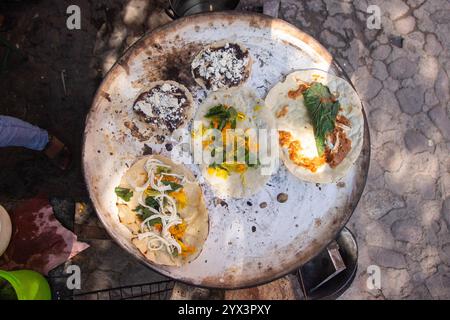 Mexikanische Quesadillas mit Tomaten, Kürbisblüten und hoja santa (Piper auritum) auf einem traditionellen Grill über dem Feuer gekocht. Stockfoto