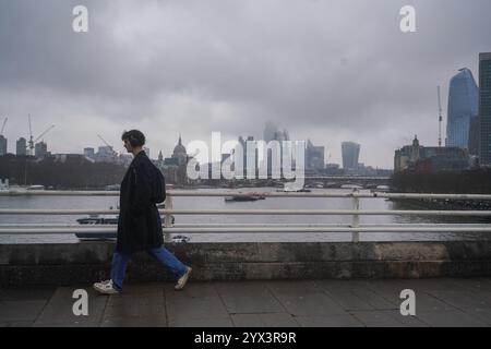 London, Großbritannien. 13. Dezember 2024 Fußgänger laufen an einem kalten Dezembermorgen auf der Waterloo Bridge mit Blick auf die Skyline und das Finanzviertel der Stadt London unter bewölktem Himmel. Die Zahlen des Office for National Statistics (ONS) zeigen, dass die britische Wirtschaft einen zweiten Monat in Folge um 0,1 % geschrumpft ist, weil sie sich Sorgen über das Budget von Kanzlerin Rachel Reeves für Oktober gemacht hat und dass die Aktivitäten in Pubs und Restaurants aus dem Einzelhandel und dem Gastgewerbe zurückgegangen sind.Credit.Amer Ghazzal/Alamy Live News Stockfoto