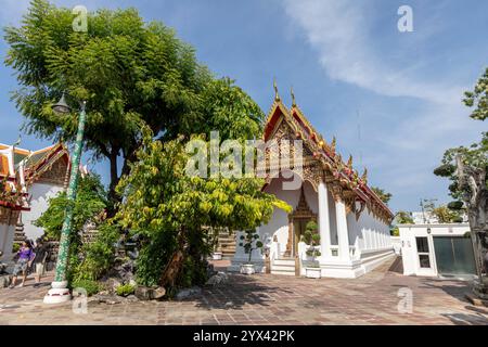 Prunkvoller Tempelsaal neben einem belaubten Baum und einem schattigen Innenhof im Wat Pho, Bangkok, Thailand Stockfoto