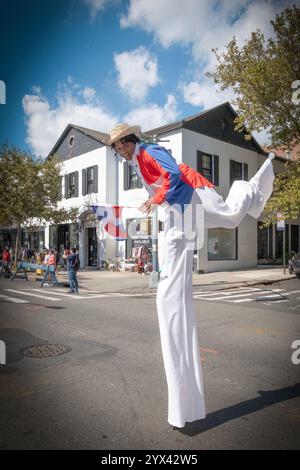 Ein Marscher, der auf Stelzen balanciert und eine Flagge hält bei der Dominican Day Parade 2024 auf der 37th Avenue in Jackson Heights, Queens, New York. Stockfoto