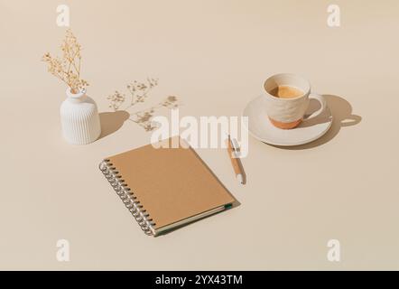 Trendiges Layout mit Tasse Kaffee, weißer Vase mit trockenen Blumen, Notizbuch und Stift auf pastellfarbenen Hintergrund. Minimales kreatives Konzept. Stockfoto