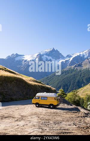 Retro-Wohnmobil im Wald mit hohen Bergen im Hintergrund, Ecrins-Nationalpark, Frankreich Stockfoto