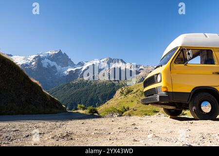 Retro-Wohnmobil im Wald mit hohen Bergen im Hintergrund, Ecrins-Nationalpark, Frankreich Stockfoto