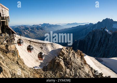 CHAMONIX, FRANKREICH - AUGUST 2023: Seilbahnbahnen, die an einem sonnigen Morgen in der Nähe des Mont Blanc in Chamonix, Frankreich, über felsige Alpen fahren Stockfoto