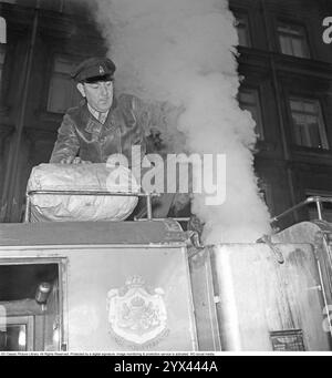 Holzgas 1942. Ein Mann füllt mehr Kohle in den Container, um die Holzgaseinheit seines LKW zu betanken. Ein natürliches Merkmal während dieser Jahre während des Zweiten Weltkriegs war die Wood-Vergasungseinheit auf Autos und Lkws. Holzgas ist ein Gas, das bei der unvollständigen Verbrennung von Holz oder Kohle entsteht und zum Antrieb von Fahrzeugen verwendet wurde. Der Fahrer musste die Kohle selbst auffüllen und sicherstellen, dass die Verbrennung ordnungsgemäß funktioniert. Aufgrund des Treibstoffmangels während des Zweiten Weltkriegs spielte Holzgas eine wichtige Rolle für den Fortbestand des Transports. Kristoffersson Ref. A117-6 Stockfoto