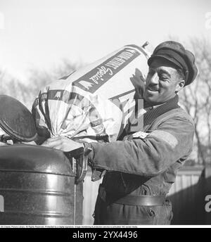Holzgas 1945. Ein Mann an einer Shell-Tankstelle füllt mehr Kohle in den Container, um die Holzgaseinheit eines LKW zu betanken. Ein natürliches Merkmal während dieser Jahre während des Zweiten Weltkriegs war die Wood-Vergasungseinheit auf Autos und Lkws. Holzgas ist ein Gas, das bei der unvollständigen Verbrennung von Holz oder Kohle entsteht und zum Antrieb von Fahrzeugen verwendet wurde. Der Fahrer musste die Kohle selbst auffüllen und sicherstellen, dass die Verbrennung ordnungsgemäß funktioniert. Aufgrund des Treibstoffmangels während des Zweiten Weltkriegs spielte Holzgas eine wichtige Rolle für den Fortbestand des Transports. Kristoffersson Ref. N50-3 Stockfoto
