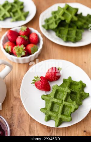 Eine lebendige und nahrhafte Frühstücksszene mit grünen Waffeln, frischen Erdbeeren und einer Tasse Kaffee, perfekt für ein gesundes und köstliches Frühstück Stockfoto