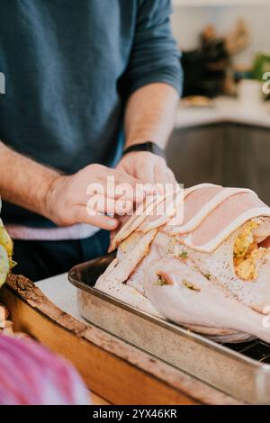 Ein Mann bereitet einen truthahn für Thanksgiving-Dinner vor. Er schneidet den truthahn und legt ihn in eine Pfanne Stockfoto