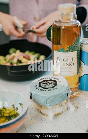 Eine Flasche Whisky steht neben einer Schüssel mit Lebensmitteln auf einer Theke. Die Flasche ist mit dem Namen „Wight Whisky“ gekennzeichnet. Stockfoto