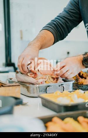 Ein Mann bereitet einen Braten in einer Pfanne zu. Die Pfanne liegt auf einem Tisch mit anderen Lebensmitteln Stockfoto