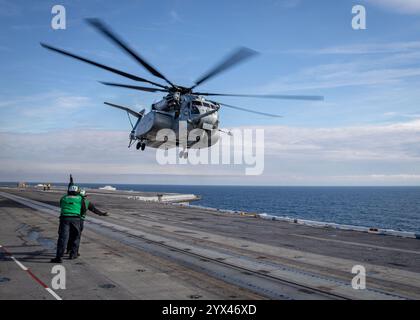 241210-N-SK738-1102 ATLANTISCHER OZEAN (10. Dezember 2024) Seeleute, die dem Flugzeugträger USS George H.W. Bush (CVN 77) der Nimitz-Klasse zugeordnet sind, signalisieren eine MH-53 Stockfoto