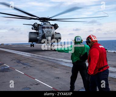 241210-N-SK738-1188 ATLANTISCHER OZEAN (10. Dezember 2024) Seeleute, die dem Flugzeugträger USS George H.W. Bush (CVN 77) der Nimitz-Klasse zugeordnet sind, signalisieren eine MH-53 Stockfoto