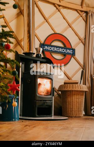 Ein Holzofen steht vor einem Weihnachtsbaum. Ein Schild mit der Aufschrift Underground hängt an der Wand Stockfoto