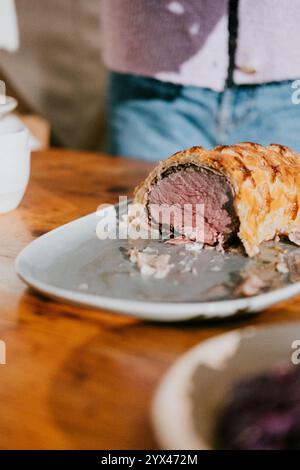 Ein Teller Fleisch steht auf einem Holztisch. Das Fleisch wird in Stücke geschnitten und auf einem weißen Teller serviert Stockfoto