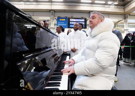 Tony Mortimer überrascht Pendler am St Pancras International Station in London mit einem Pop-up-Auftritt seiner Nummer eins zu Weihnachten 1994, „Stay Another Day“, unterstützt vom London Community Gospel Choir. Tony arbeitet mit der Musiktherapie-Wohltätigkeitsorganisation Nordoff und Robbins zusammen, um den 30. Jahrestag der Veröffentlichung des Songs zu feiern. Bilddatum: Freitag, 13. Dezember 2024. Stockfoto