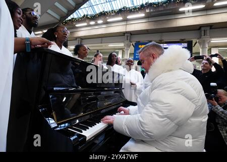 Tony Mortimer überrascht Pendler am St Pancras International Station in London mit einem Pop-up-Auftritt seiner Nummer eins zu Weihnachten 1994, „Stay Another Day“, unterstützt vom London Community Gospel Choir. Tony arbeitet mit der Musiktherapie-Wohltätigkeitsorganisation Nordoff und Robbins zusammen, um den 30. Jahrestag der Veröffentlichung des Songs zu feiern. Bilddatum: Freitag, 13. Dezember 2024. Stockfoto