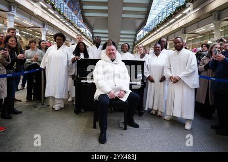 Tony Mortimer überrascht Pendler am St Pancras International Station in London mit einem Pop-up-Auftritt seiner Nummer eins zu Weihnachten 1994, „Stay Another Day“, unterstützt vom London Community Gospel Choir. Tony arbeitet mit der Musiktherapie-Wohltätigkeitsorganisation Nordoff und Robbins zusammen, um den 30. Jahrestag der Veröffentlichung des Songs zu feiern. Bilddatum: Freitag, 13. Dezember 2024. Stockfoto