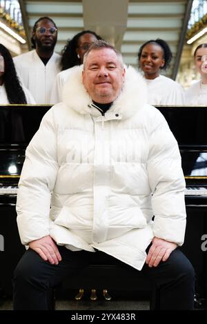 Tony Mortimer überrascht Pendler am St Pancras International Station in London mit einem Pop-up-Auftritt seiner Nummer eins zu Weihnachten 1994, „Stay Another Day“, unterstützt vom London Community Gospel Choir. Tony arbeitet mit der Musiktherapie-Wohltätigkeitsorganisation Nordoff und Robbins zusammen, um den 30. Jahrestag der Veröffentlichung des Songs zu feiern. Bilddatum: Freitag, 13. Dezember 2024. Stockfoto