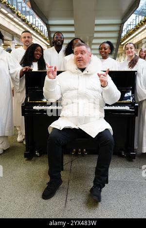 Tony Mortimer überrascht Pendler am St Pancras International Station in London mit einem Pop-up-Auftritt seiner Nummer eins zu Weihnachten 1994, „Stay Another Day“, unterstützt vom London Community Gospel Choir. Tony arbeitet mit der Musiktherapie-Wohltätigkeitsorganisation Nordoff und Robbins zusammen, um den 30. Jahrestag der Veröffentlichung des Songs zu feiern. Bilddatum: Freitag, 13. Dezember 2024. Stockfoto