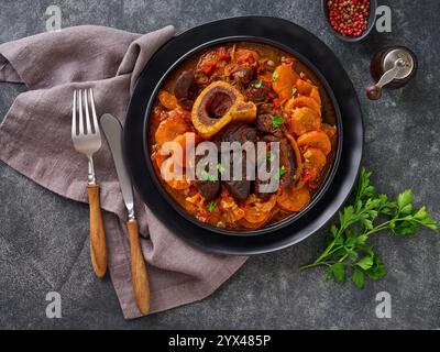 Ossobuco. Steak Kalbsbacken oder Eintopf mit Gemüsesauce und Gewürzen auf einem alten Betontisch Hintergrund. Italienische Küche Hintergrund mit Zutaten. Stockfoto