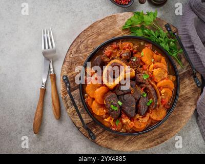 Ossobuco. Steak Kalbsbacken oder Eintopf mit Gemüsesauce und Gewürzen auf einem alten Betontisch Hintergrund. Italienische Küche Hintergrund mit Zutaten. Stockfoto