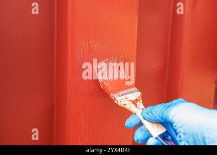 Eine Hand mit einem Pinsel malt eine alte Eisenoberfläche mit Farbe. Stockfoto