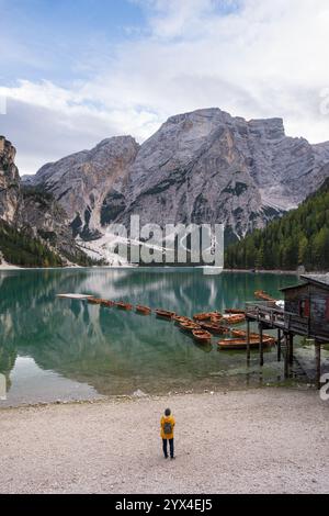 Frau in gelbem Regenmantel genießt die Landschaft am Pragser See in den Pragser Dolomiten in Südtirol, Italien. Stockfoto