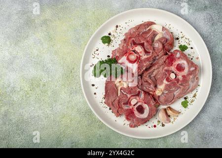 Rohes Steak, Kalbhals auf den Knochen, frisches Fleisch, auf einem weißen Teller, Blick von oben, keine Leute Stockfoto