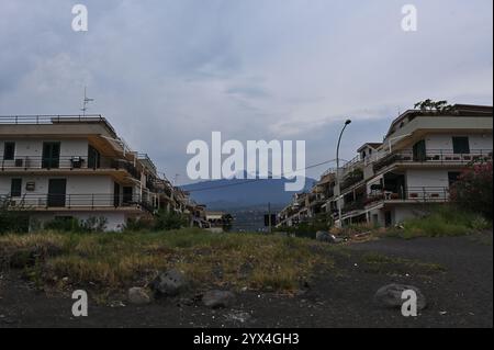 Blick auf den Ätna vom Giarre Beach. Ein malerischer Blick auf den Ätna vom Strand Giarre, Sizilien, mit Palmen und schattigen Häusern im Vordergrund. Stockfoto