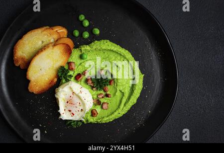 Erbsenpüree, mit gekochtem Ei, gebratenem Speck, Toast, Baguette, Frühstück, hausgemacht, keine Leute Stockfoto