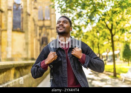 Afrikanischer Mann lächelt, während er eine Stadt entlang spaziert Stockfoto