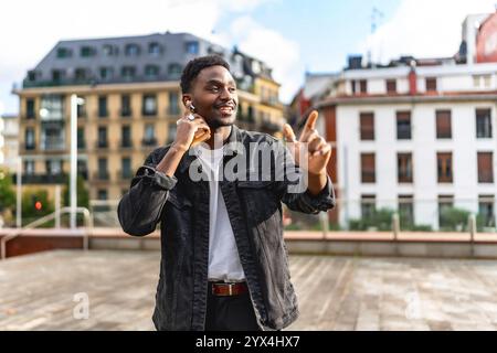 Cooler afrikanischer Mann, der in der Stadt Musik mit Ohrstöpseln hört Stockfoto