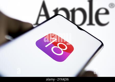 Apple IOS 18-Symbol auf dem Smartphone und Apple-Logo auf dem Hintergrund. Stockfoto