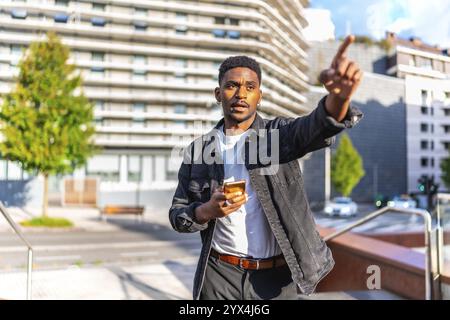 Afrikanischer Mann, der mit der gps-App in der Stadt auf eine Richtung zeigt Stockfoto