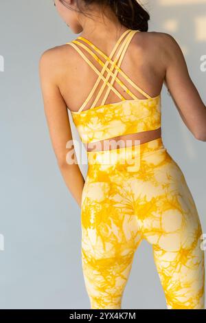 Nahaufnahme einer Frau, die in gelben Marmor-Leggings und leuchtend orangefarbenen Sportschuhen steht, ideal für Fitness- und Modethemen. Stockfoto
