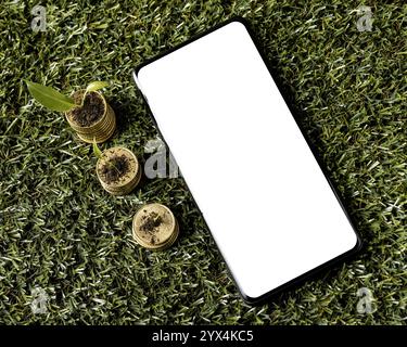 Draufsicht drei Stapel Münzen Gras mit Smartphone Stockfoto