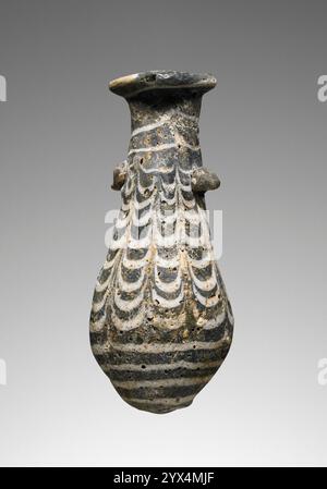 Alabastron, 2.-1. Jahrhundert v. Chr. Zusätzliche Info: Kernförmiges, dunkelblaues Alabastron mit einem gekämmten Muster. Ein weißer Faden spiralisiert sich um den Oberkörper, der sich um den Mundrand fortsetzt. Ein weißer Faden spiralisiert sich ebenfalls um den unteren Körper. Am Hals sind zwei Haltegriffe, einer auf jeder Seite, befestigt. Das Gefäß weist Anzeichen von Verwitterung und Verfärbungen auf. Die Oberfläche weist einige Abschürfungen und Kerben auf. Stockfoto