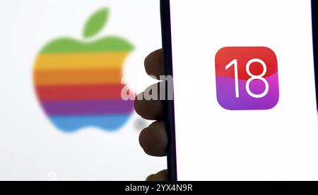 Apple IOS 18-Symbol auf dem Smartphone und Apple-Logo auf dem Hintergrund. Stockfoto