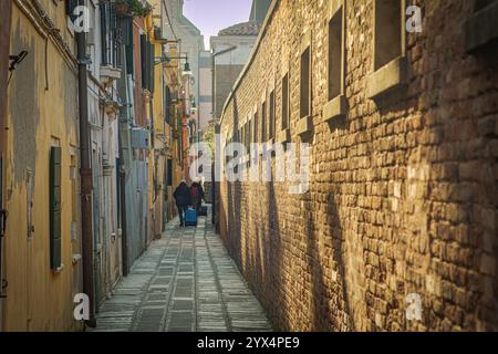 Venedig, Italien. Touristen in einer engen Gasse, die nach der Tür zu ihrem Resort in Cannaregio, einem historischen Viertel der Stadt, suchen. Stockfoto