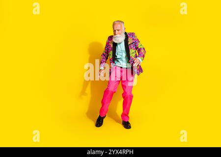 Foto in voller Größe von hübschem Rentner Mister tanzen Genießen Sie Party gekleidete stilvolle bunte rosa klassische Kleidung isoliert auf gelbem Hintergrund Stockfoto