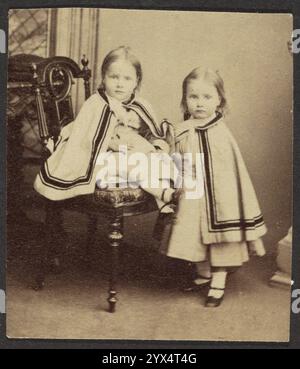 Porträt zweier Mädchen in Matching Capes, Ende des 19. Jahrhunderts. Zusätzliche Info: Porträt zweier Mädchen (eines sitzend, eines stehend) in passenden Umhängen. Stockfoto