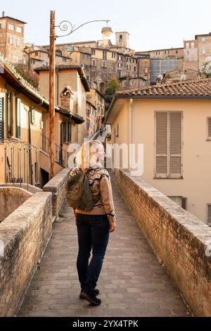Junge blonde Europäerin, die durch die Straßen der Altstadt von Perugia in Umbrien, Italien, spaziert. Vertikale Ausrichtung Stockfoto