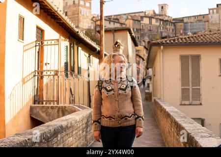 Junge blonde Europäerin, die durch die Straßen der Altstadt von Perugia in Umbrien, Italien, spaziert. Stockfoto