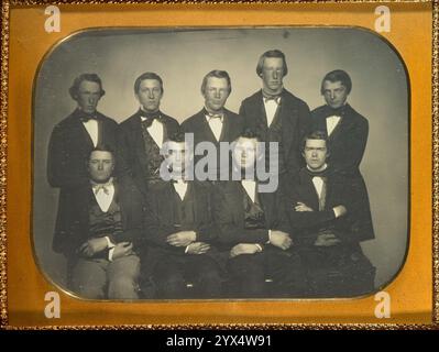 Gruppenporträt von neun jungen Männern, um 1850. Weitere Informationen: Fünf Männer stehen, vier Männer sitzen, ein zweiter von rechts sitzender Mann hat Kinnbart. Einfarbiger Hintergrund. Stockfoto