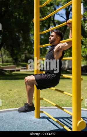 Fitter junger Mann, der Bauchübungen an Außenbars macht Stockfoto
