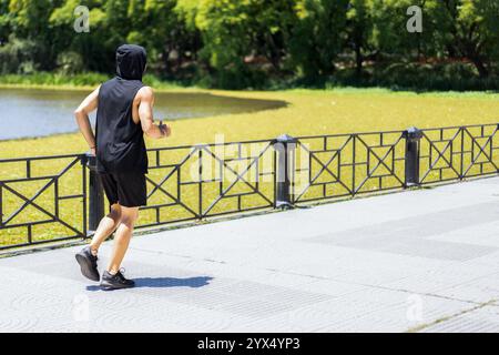 Fitter junger Mann genießt einen erfrischenden Lauf am See im Stadtpark. Stockfoto