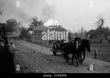 Russland 1943 Rückzug deutscher Soldaten auf Pferdewagen vor brennenden Häusern in einem Dorf am Dnieper in der Region Zosch. Aufgrund der verbrannten Erdordnung wurden Siedlungen und Vorräte während des Rückzugs zerstört. Army Group Center, im Bereich der 110. Infanteriedivision. [Automatisierte Übersetzung] Stockfoto